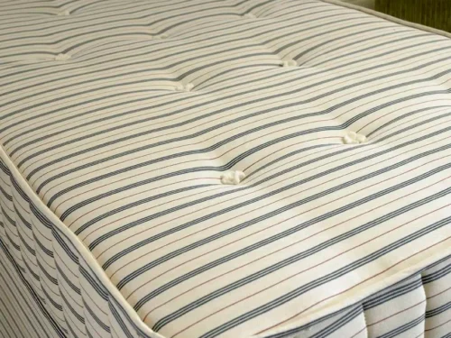 A close-up of a stripy, tufted mattress.